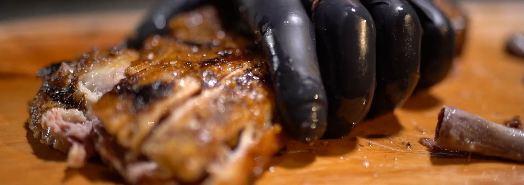 Black glove holding and slicing barbeque chicken