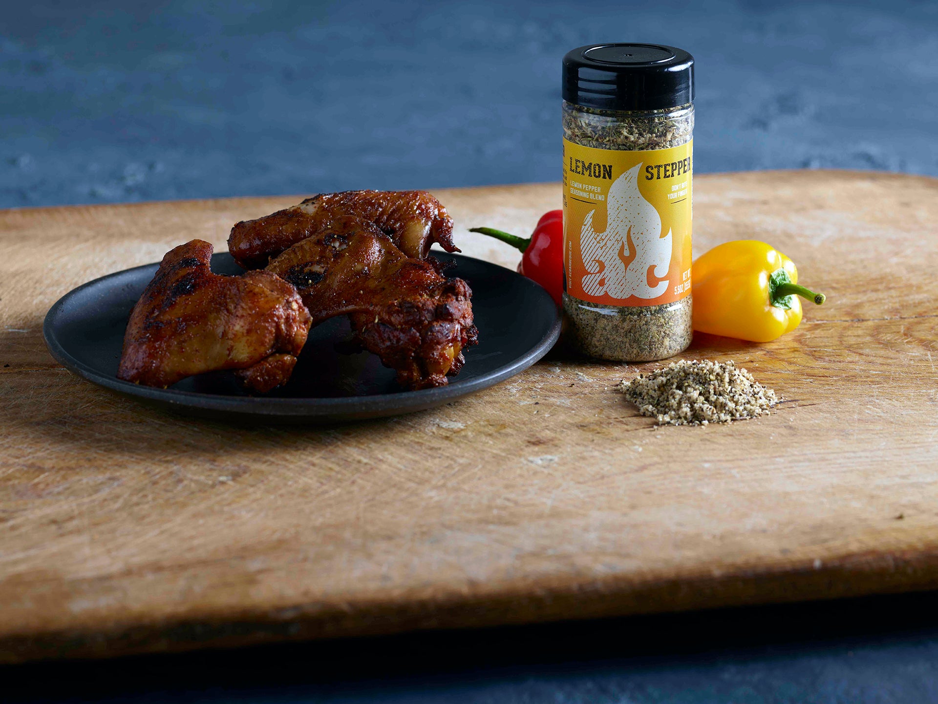 Lemon Stepper Seasoning Rub by AC Barbeque next to a plate with seasoned and cooked chicken